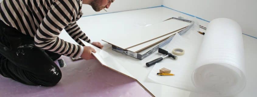 Renovations contractor placing white laminate flooring in Hamilton basement