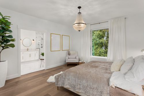 Beautiful Master Bedroom in New Luxury Home. Features Elegant Pendant Light, Hardwood Floors, and View of Ensuite Master Bathroom